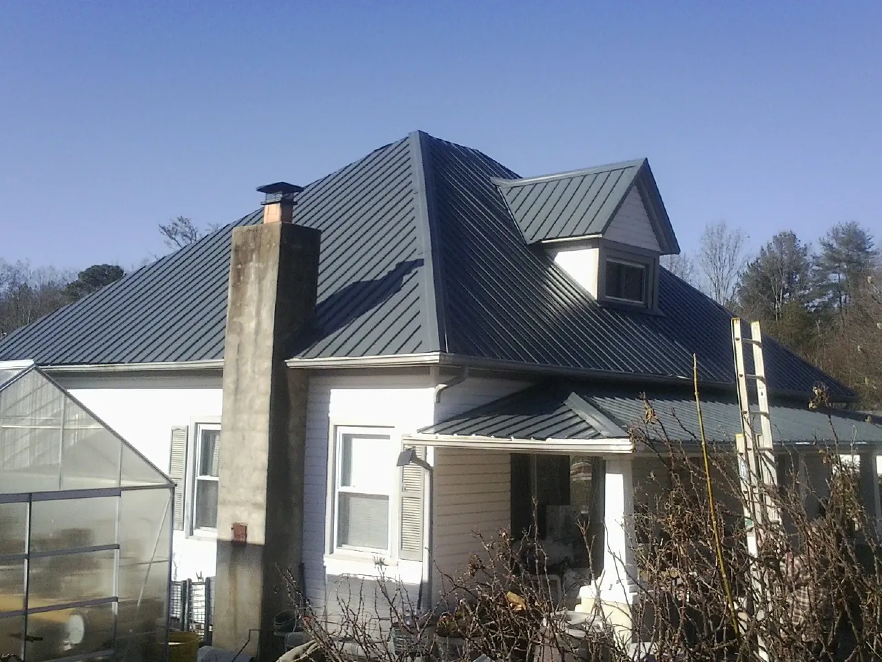 Dark blue standing seam metal roof on a white farmhouse with dormer — Slate & Tile Roof Repair by Roofing Brothers in Saint George