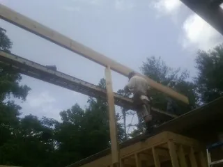 Carpenter setting a ridge beam over a new addition frame — Ice Dam Removal by Roofing Brothers in Saint George