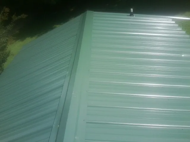 New green metal panels meeting at the ridge of a roof — Flat Roof Repair work by our crew in Saint George