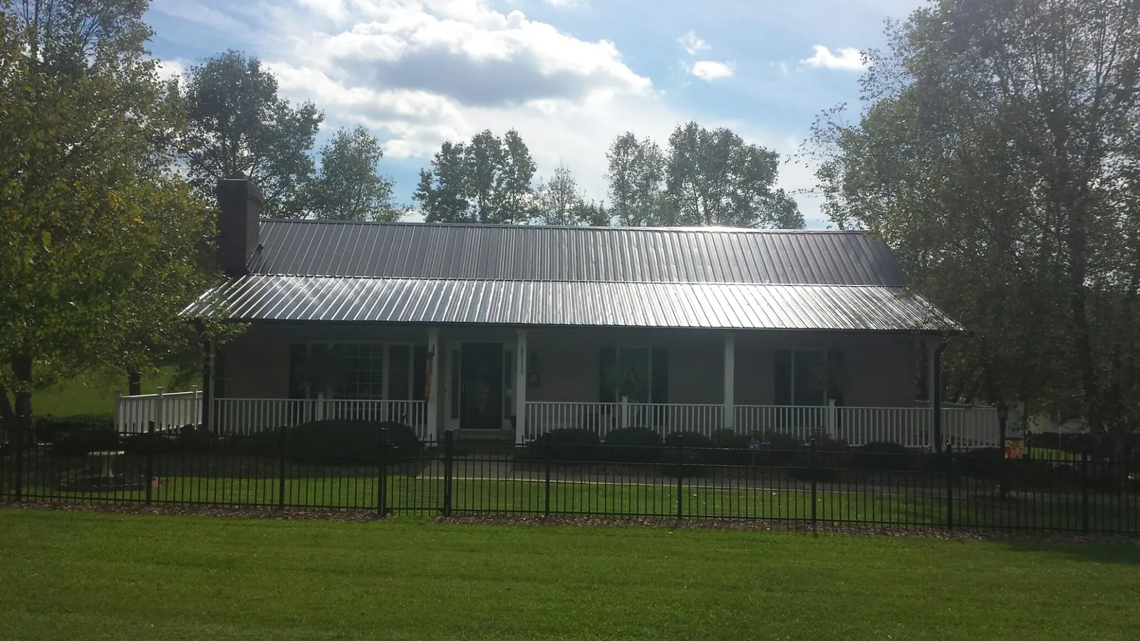 Gray metal roof on a brick ranch with a full width front porch — Gutter Guard Installation work by our crew in Saint George