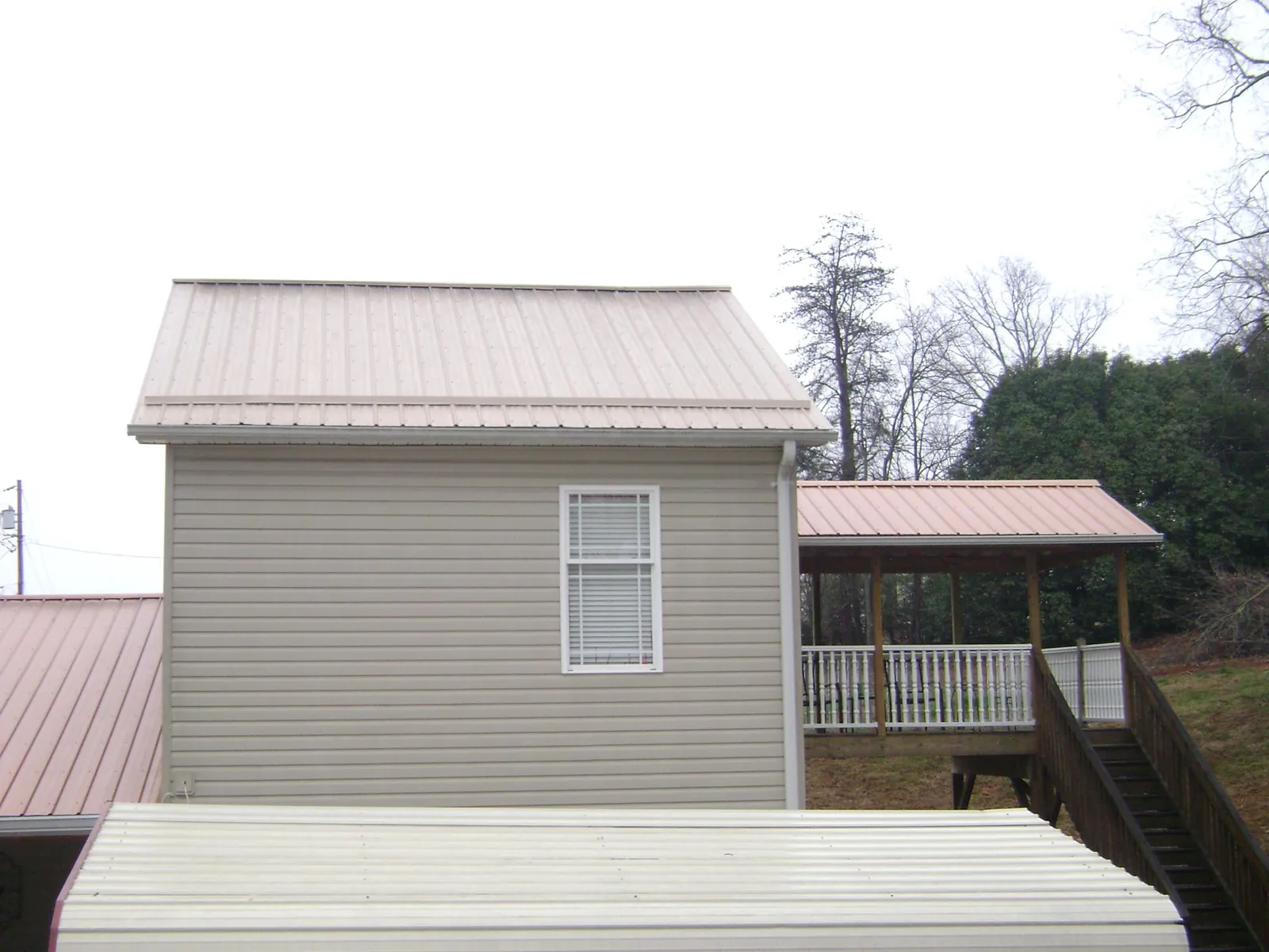 Tan metal roofs on a two story addition and attached porch, from a Roof Replacement job in Saint George